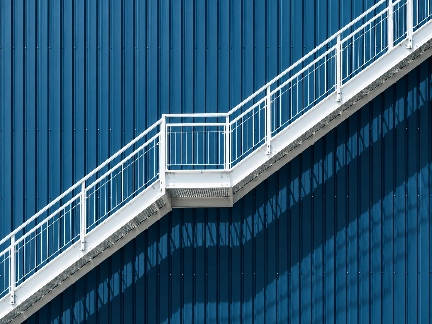 Escalier industriel blanc sur une façade bleue